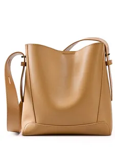 Braune Beuteltasche aus echtem Leder mit breitem Gurt auf weißem Grund, 2025 Luxus-Stil
