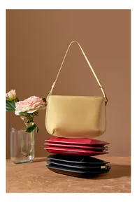Three minimalist leather handbags in yellow, red, and black stacked in a creative layout