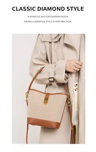 Detail view of a canvas bucket bag with brown leather trim and golden metal lock