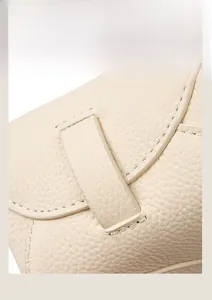 Détail de la découpe latérale et des coutures sur un sac en cuir grainé blanc cassé