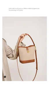 Close-up of beige canvas bucket bag with brown leather trim and golden metal turn-lock