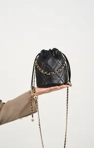 Details einer schwarzen gesteppten Leder-Beuteltasche mit goldener Kette und Kugel