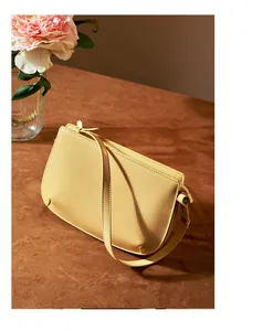 Chic light yellow leather underarm bag displayed with pink peonies in a lifestyle setting