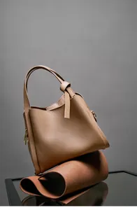 Dettaglio borsa a secchiello in pelle martellata color cuoio con manico annodato e oro