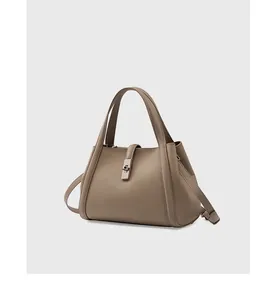 Detailed macro view of the pebbled taupe leather texture and silver buckle on the tote bag