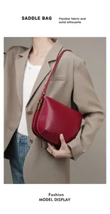 Detailed close-up of dark red leather saddle bag with adjustable strap and gold hardware