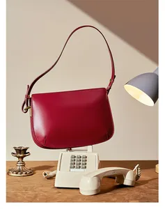 Detailed view of luxury dark red leather shoulder bag on a vintage phone stand