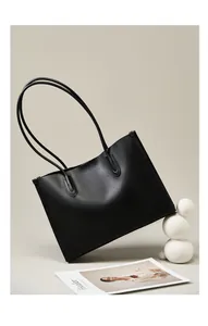 Detalle de bolso tote minimalista de cuero negro con correas largas y acabado mate