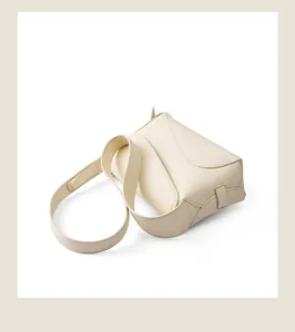 Détail du cuir grainé de qualité sur un sac bandoulière blanc crème aux finitions lisses