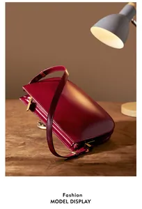 Detail of dark red glossy leather shoulder bag with elegant gold metal zipper and buckle