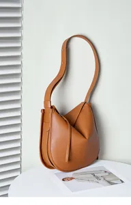 Detail of caramel leather tote featuring a unique folded base and adjustable strap