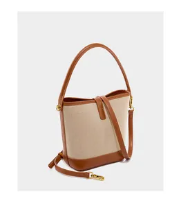 Detail view of canvas and brown leather stitching on a stylish bucket handbag