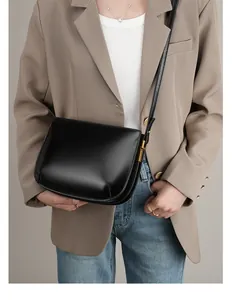 Detail of minimalist black leather half-moon bag with elegant vintage gold hardware accents