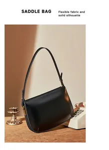 Detail of minimalist black leather saddle bag with adjustable strap and metal hardware
