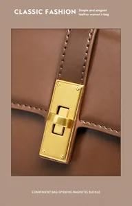 Detail of matte gold magnetic buckle on caramel leather bag with fine stitching