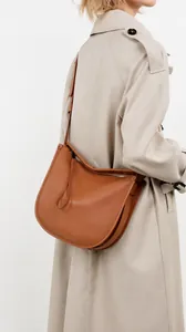Detail of tan leather hobo bag stitching and long tassel zipper on a trench coat model