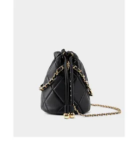 Detail der schwarzen gesteppten Beuteltasche mit Goldkette und goldenem Kugel-Accessoire
