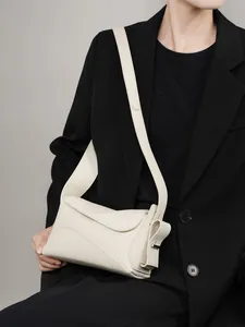 Sac hobo minimaliste en cuir beige avec large bandoulière présenté sur un mannequin