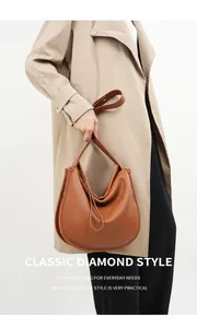 Brown leather slouchy hobo bag shown on model wearing a trench coat for chic style