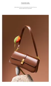 Detailed close-up of brown leather shoulder bag with golden metallic twist lock buckle