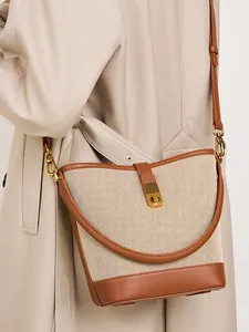 Chic woven canvas and leather bucket bag shown on a trench coat for everyday style