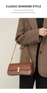 Detailed close-up of brown leather baguette bag with premium gold square clasp and flap