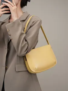 Minimalist bright yellow cowhide leather underarm bag shown on model in a studio