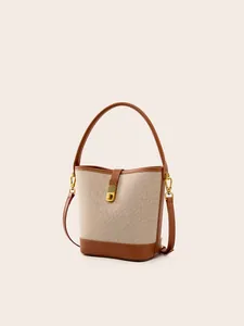 Minimalist canvas bucket bag with brown leather trim and golden metal clasp for women