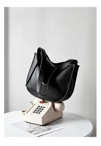 Detail of adjustable wide leather strap and zipper closure on a black minimalist hobo bag