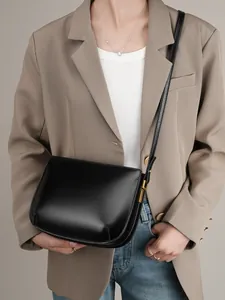 Elegant black genuine leather shoulder bag for women with gold hardware and saddle design