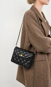 Close-up of quilted leather chain bag featuring gold floral buckle and woven strap