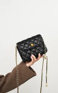 Detail of black quilted leather shoulder bag with golden flower buckle and chain