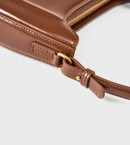 Detailopname van bruine lederen tas met gouden hardware en verfijnde stikseldetails