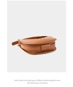 Detail view of the soft caramel leather texture and wide strap of the crescent bag