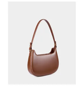 Detail van een bruine leren hobo tas in halve maanvorm met glanzende afwerking en gouden beslag