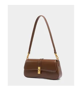 Close-up of brown leather bag featuring curved bottom and golden square metal twist lock