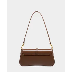 Detail view of smooth dark brown leather baguette bag with elegant golden hardware