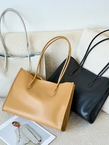 Bolsos tote grandes y minimalistas de cuero en crema, marrón y negro en un sofá suave