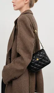 Side view of a quilted leather chain bag with golden flower buckle on a model