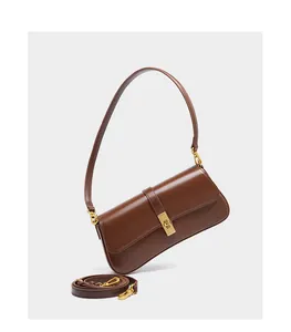 Detail of a brown leather baguette bag featuring golden square buckle and dual straps