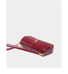 Close-up of deep red leather shoulder bag with glossy finish and gold metal hardware