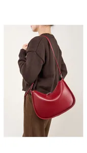 Minimalist bordeaux leather crescent underarm bag shown on a model's shoulder