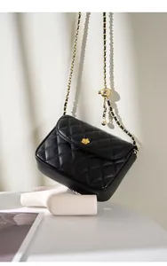 Close-up of black quilted leather bag with gold flower clasp and metal chain strap