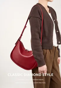 Detailed view of a red crescent shoulder bag with silver zipper and matte leather finish