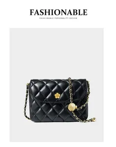 Close-up of black quilted leather texture and gold flower logo on the handbag flap