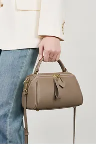 Detail of lychee pattern genuine leather texture and golden metal hardware on the grey bag