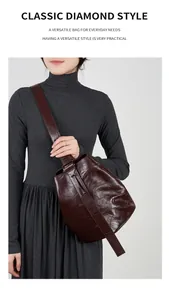 Detail einer dunkelbraunen Vintage-Leder-Eimertasche mit Falten und breitem Riemen