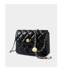 Detailed macro of black quilted leather shoulder bag with golden floral buckle and chain