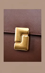 Detailed close-up of vintage distressed gold hardware buckle on brown leather bag