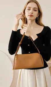 Détail d'un sac oreiller en cuir marron avec pendentif cœur porté avec une tenue décontractée